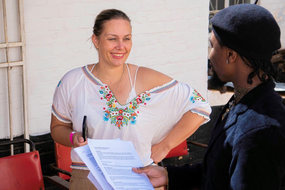 A photo of Laura Schuerwegen in a white top, smiling as talks to someone in front of her.